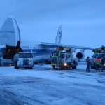 a plane with workers on the ground