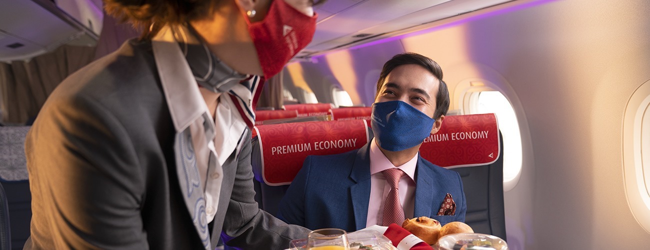 a man wearing a mask and a suit sitting in a plane