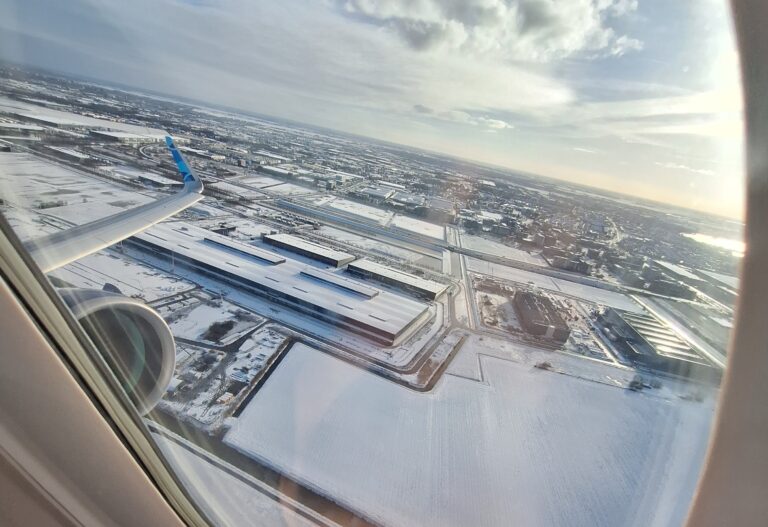 snowy airport seen out the window of a plane flying above